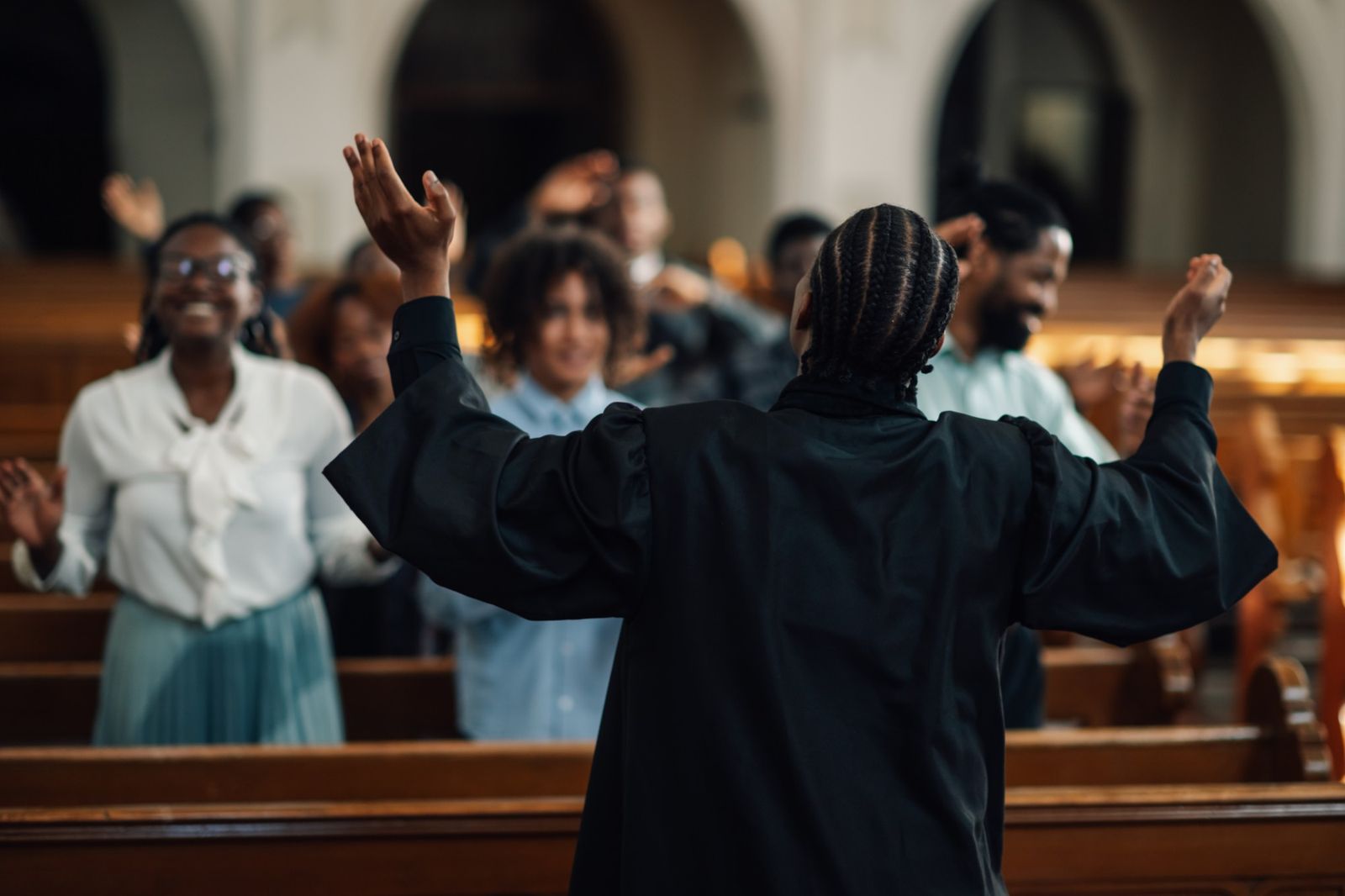 Worship leader with arms raised before a joyful congregation